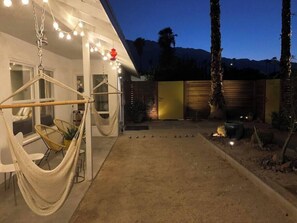 Uma casa moderna com uma rede e luzes penduradas no quintal.