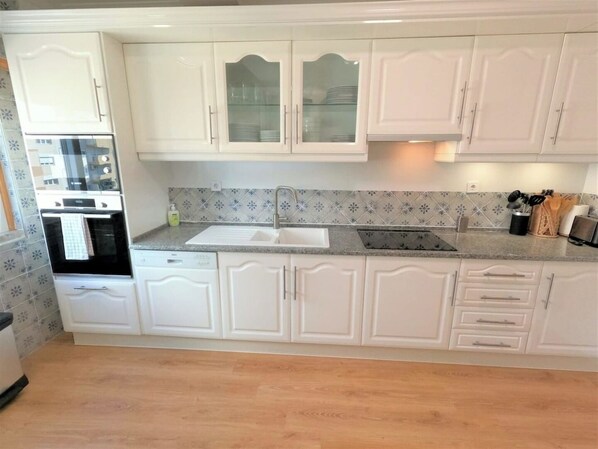 A kitchen with white cabinets, a sink, and a stove.