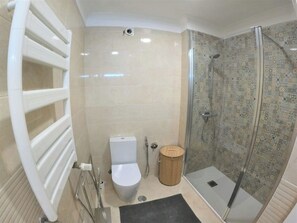 A bathroom with a toilet, shower, and a towel rack.