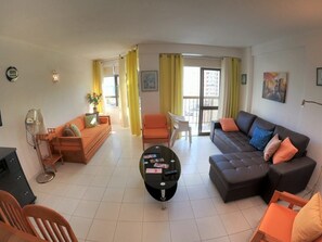 Uma sala de estar com sofá, mesa de centro e ventilador.