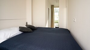 Un dormitorio con una cama grande, una ventana y una puerta que da a un espacio exterior.