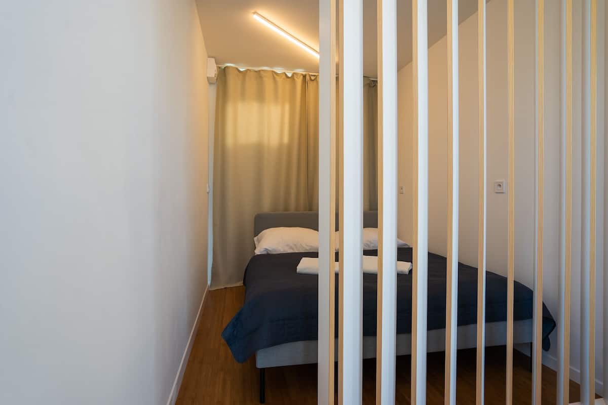 A bedroom with a bed, a curtain, and a light fixture.