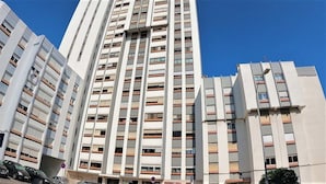 A multi-story building with a modern architectural design, featuring a series of balconies and windows. - Lisbon, T2 apartment in condominium, Linda-a-Velha (Linda a Velha)