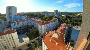 A high-rise building with multiple floors, surrounded by other buildings and greenery. - Lisbon, T2 apartment in condominium, Linda-a-Velha (Linda a Velha)