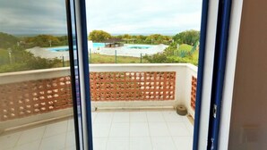 Un balcón con vistas a una piscina y follaje circundante.
