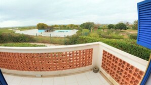 Un balcón con vista a una piscina y follaje circundante.