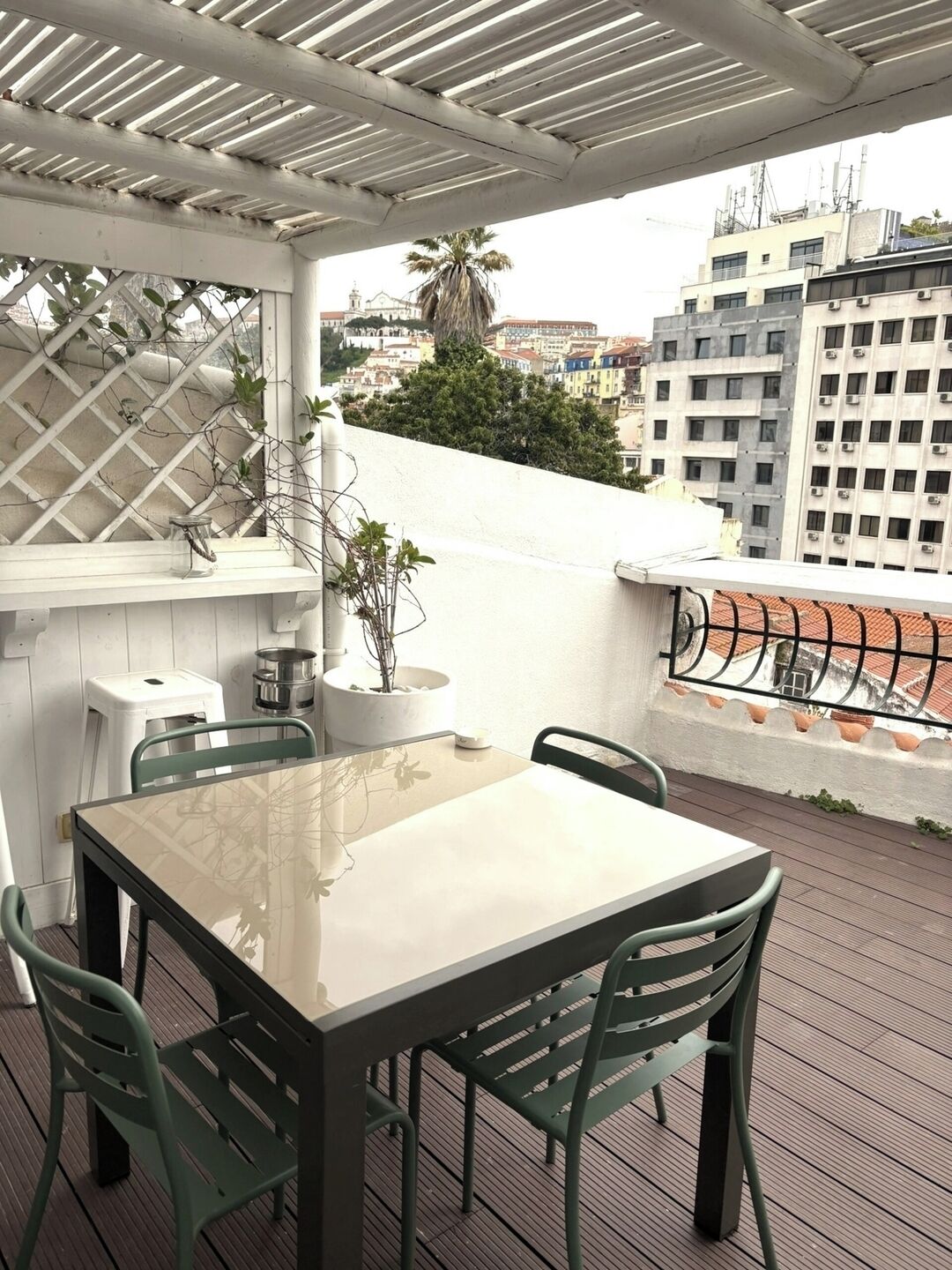 Terraza en la azotea con una mesa, sillas, una planta en maceta y vistas a edificios.