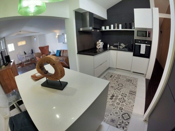 Une cuisine moderne avec des meubles blancs, un îlot central et un tapis à motifs.
