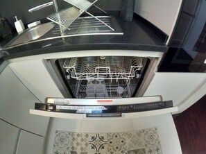 A kitchen with a dishwasher, a sink, and a patterned backsplash.