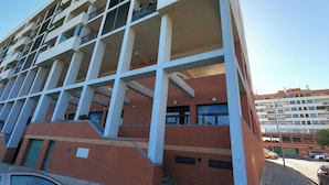 Een meerlaags gebouw met een modern architectonisch ontwerp, met een combinatie van baksteen en witte structurele elementen, en een zichtbare ingang op de begane grond.