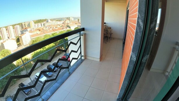 Een balkon met uitzicht op een stadsgezicht, een betegelde vloer en een trap.