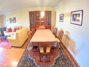 Un espace repas comprenant une table, des chaises, un canapé, un meuble et un tapis.