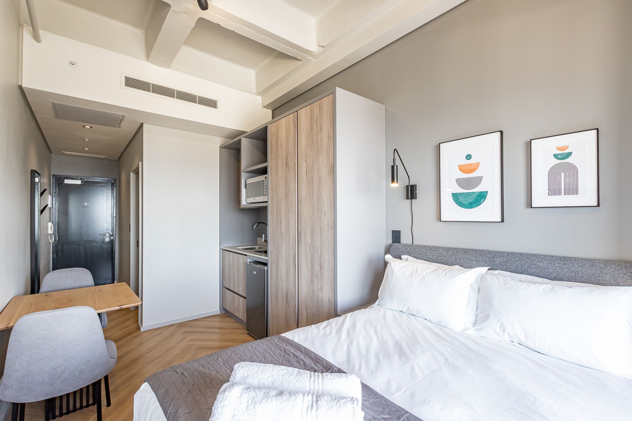 Hotelkamer met een bed, een bureau, een stoel, een garderobe, een magnetron en kunst aan de muur.