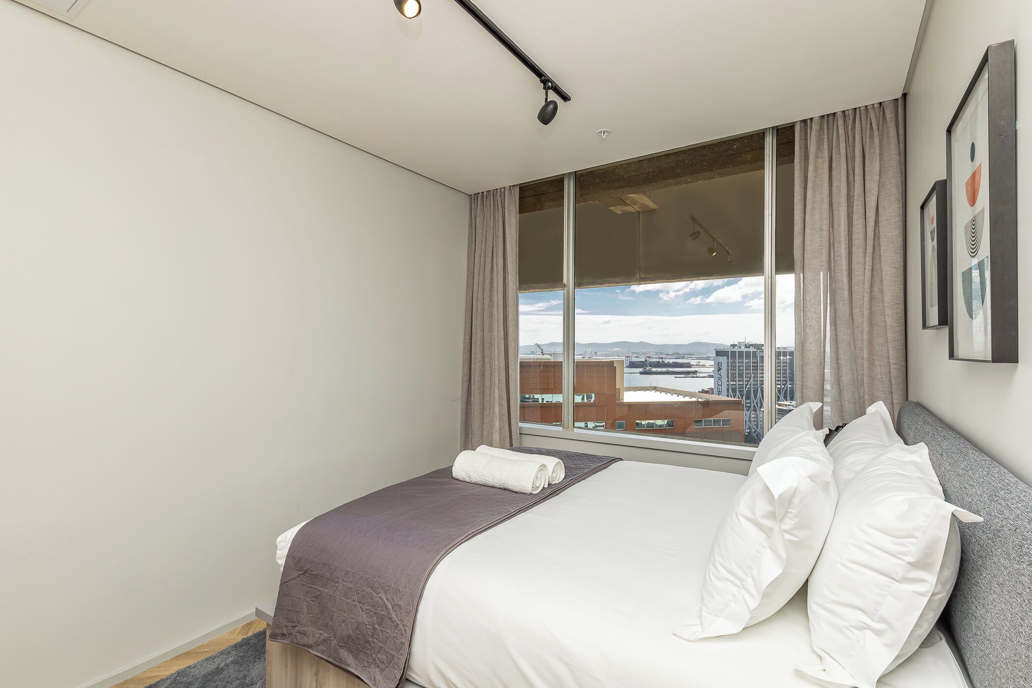 A hotel room with a large bed, a view of the city through a window, and a modern design.