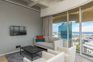 A modern living room with a sofa, a coffee table, and a large window offering a city view.
