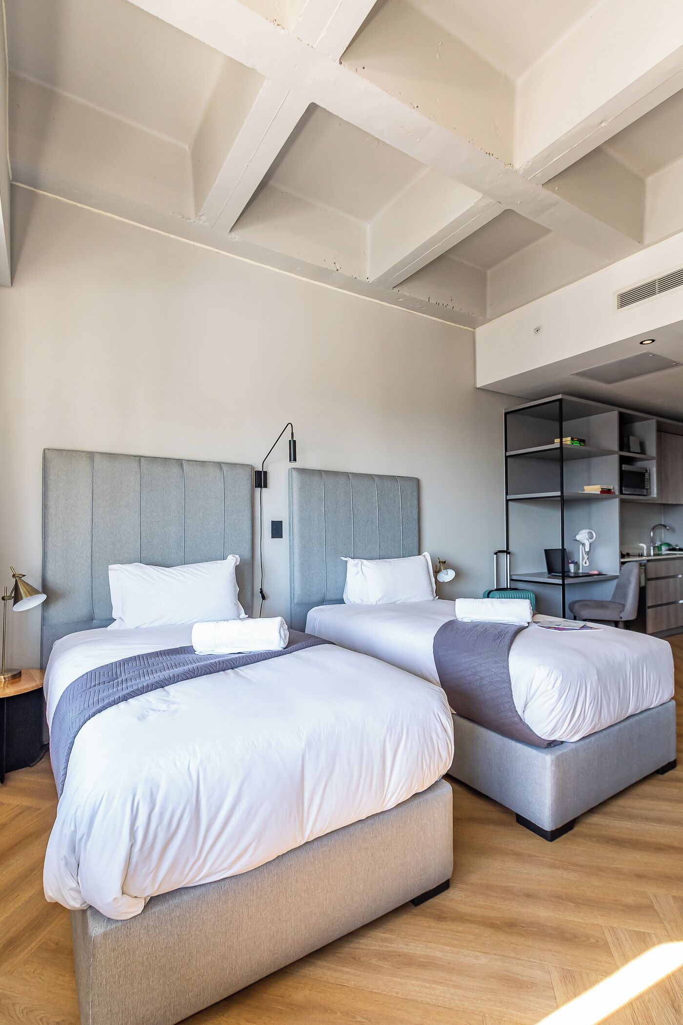 Una habitación de hotel moderna con dos camas, un escritorio y una estantería.