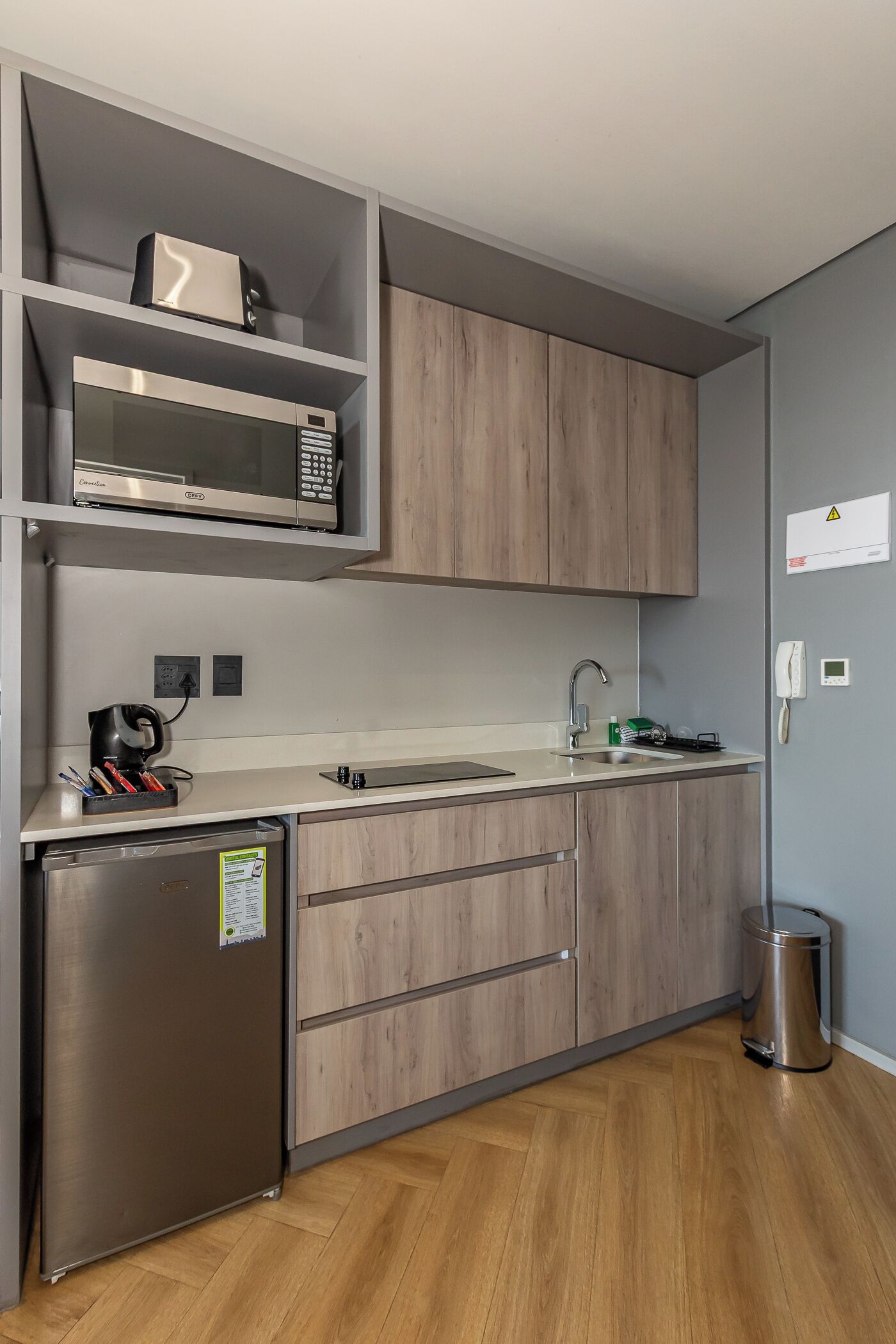 A modern kitchen with a built-in microwave, a coffee maker, and a stainless steel refrigerator.