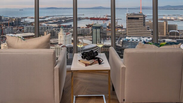 A high-rise room with a view of a port and cityscape.