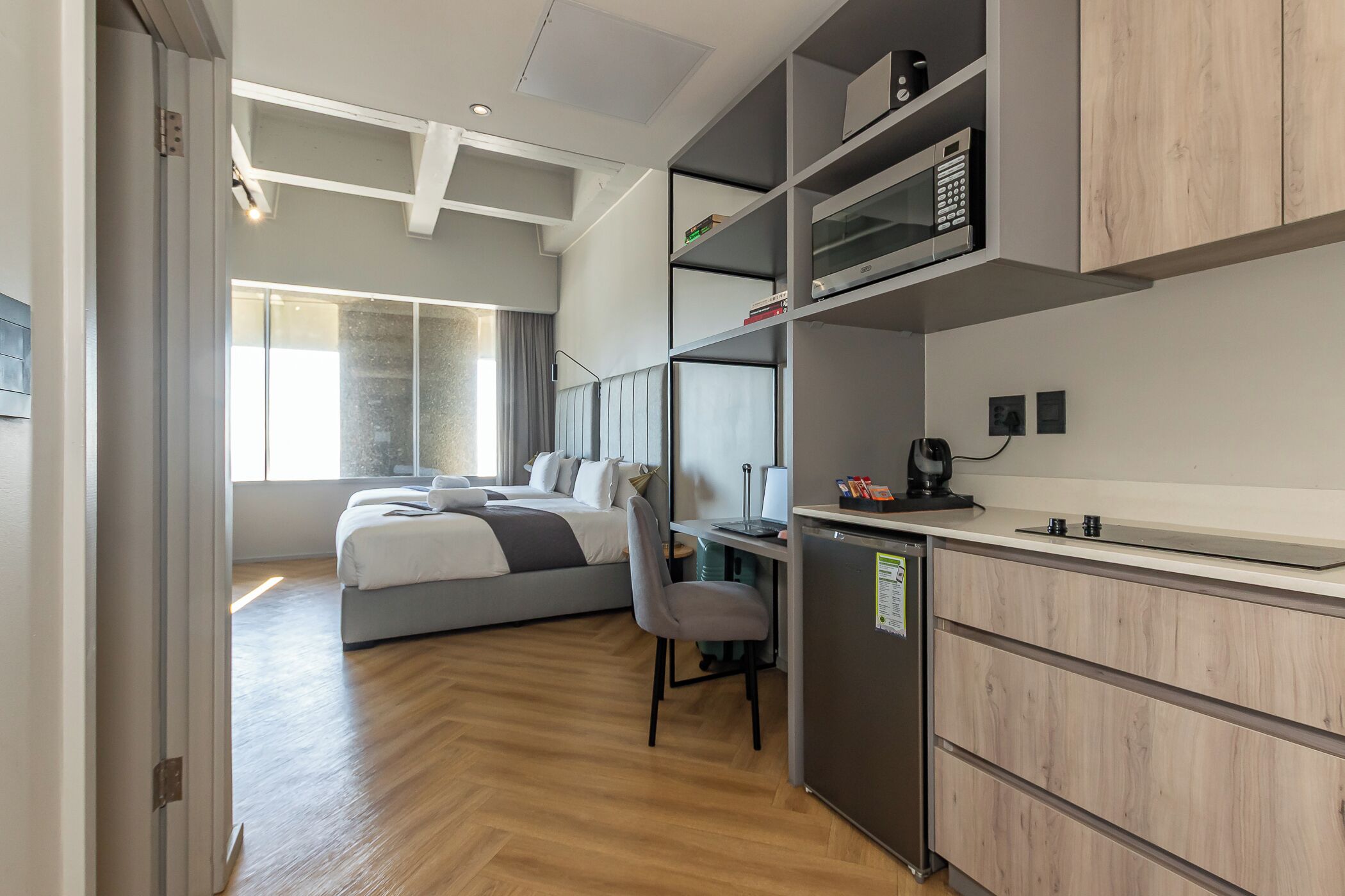 Et moderne hotelværelse med seng, skrivebord, stol og indbygget mikroovn.