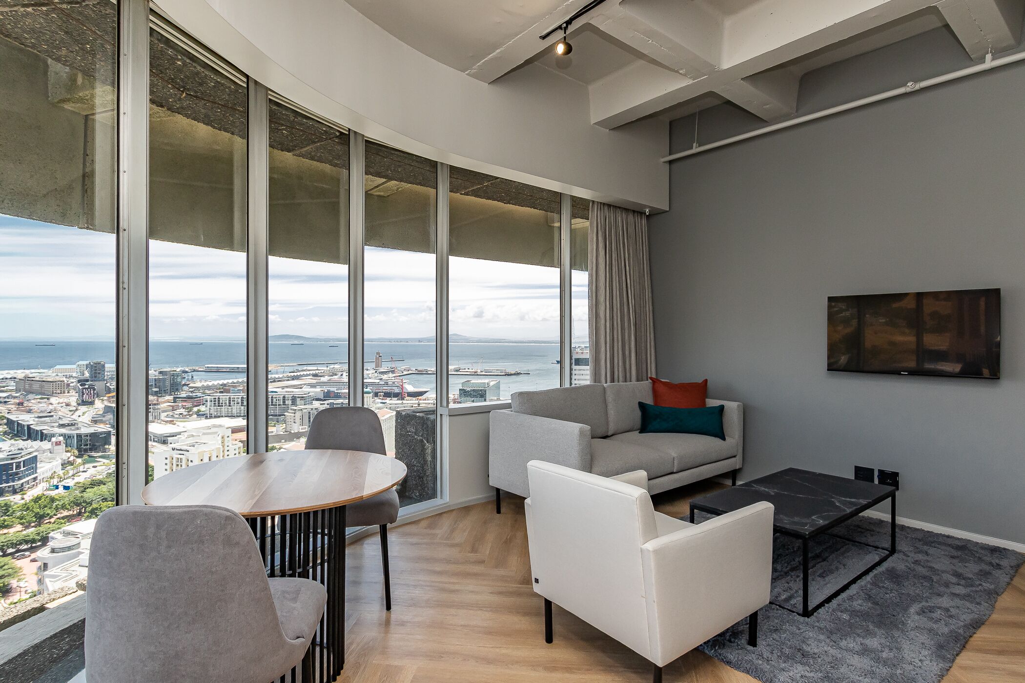 Ein modernes Wohnzimmer mit Blick auf die Stadt, einem runden Tisch und einer Couch.