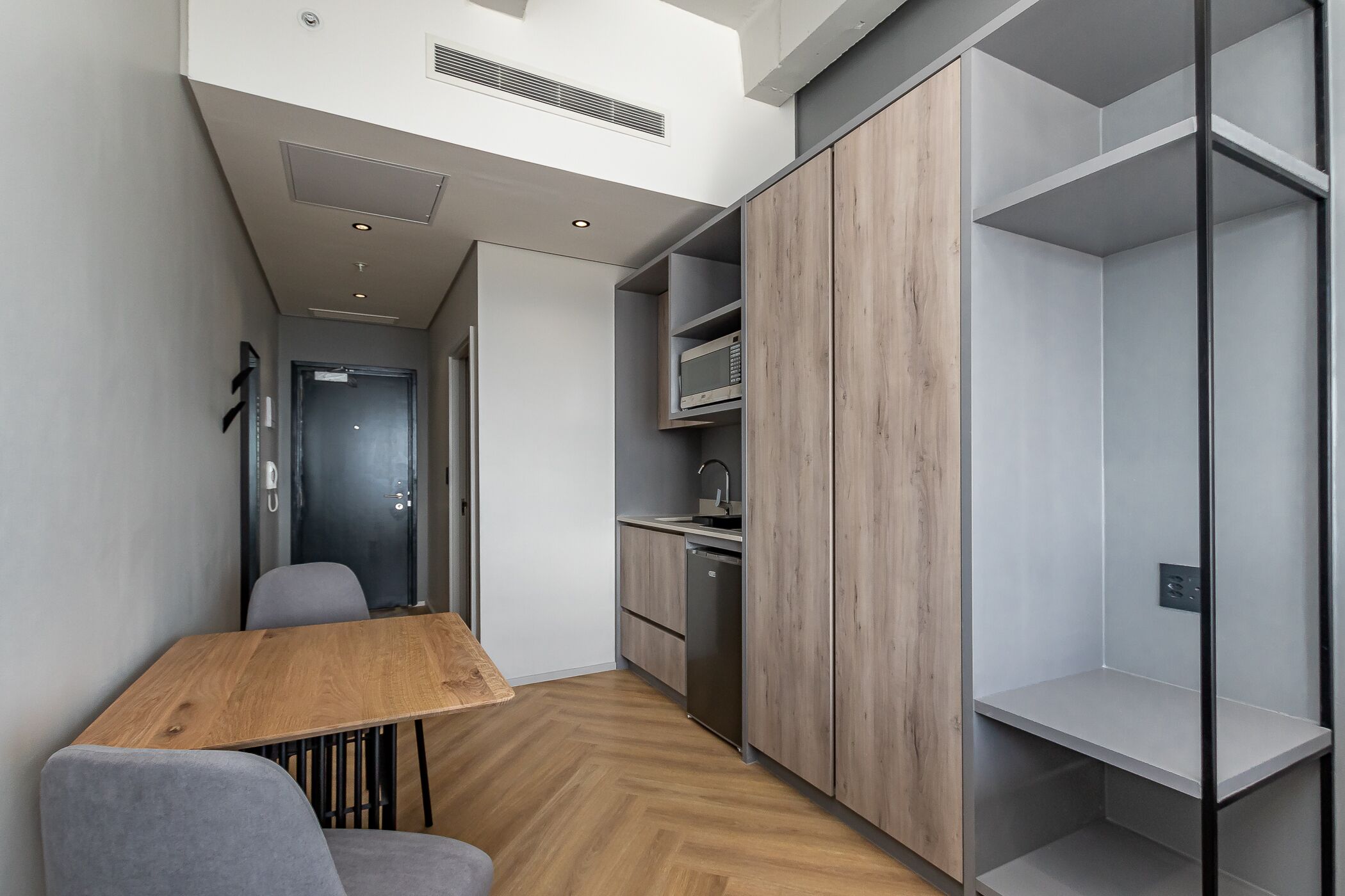 A compact kitchen with a microwave, sink, and wooden cabinets.