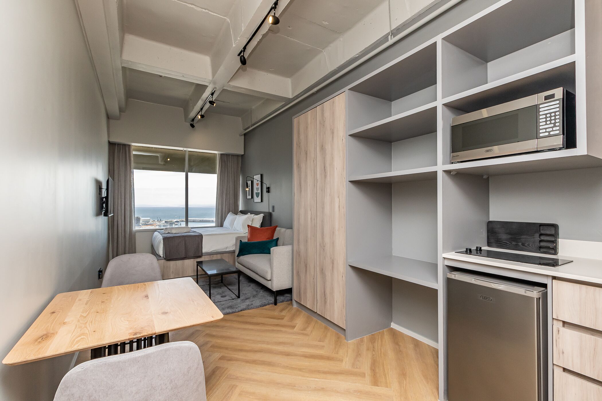 Un espace de vie compact comprenant un coin cuisine, un coin repas et un espace détente avec vue.