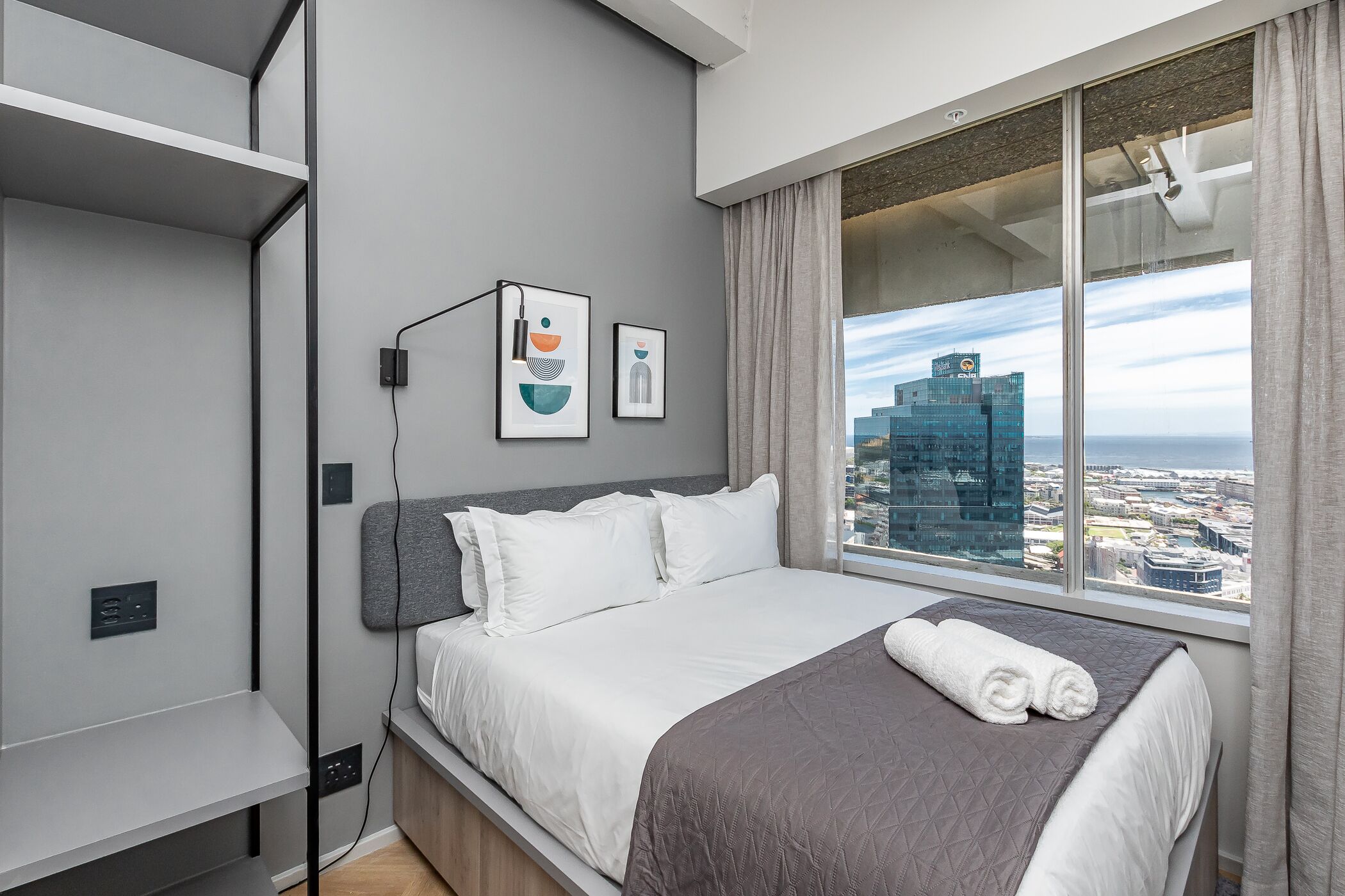 Una habitación de hotel moderna con una cama grande, vistas a la ciudad y un diseño minimalista.