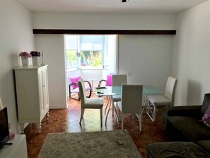A living room with a dining area, a sofa, a cabinet, and a window with a view.