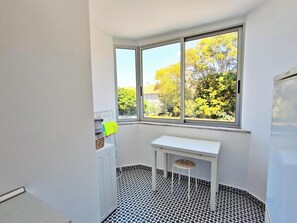 A small room with a checkered floor, a white table, and a window with a view of trees.