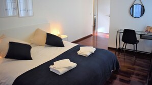 A hotel room with a bed, pillows, a desk, a chair, and a mirror. - Madeira, 3 bedroom apartment w Ocean Views Funchal (Funchal)