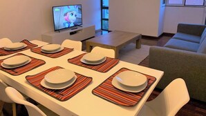 A dining area with a TV, a sofa, and a window. - Madeira, 3 bedroom apartment w Ocean Views Funchal (Funchal)