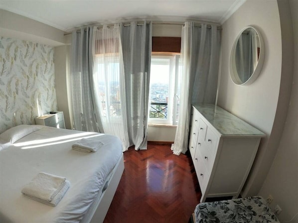 Une chambre dâhĂŽtel avec un lit, une commode, un miroir et une fenĂȘtre avec des rideaux.