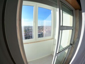 A room with a large window, a door, and a view of a cityscape. - Sintra, T3 duplex with magnificent views and balcony, Tapada das Mercês, Sintra (Algueirão)