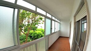 Un pasillo con amplios ventanales, suelo de baldosas y vista a zonas verdes.