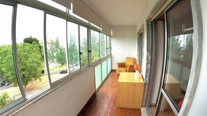 Un balcón con amplias ventanas, una mesa de madera y una silla.
