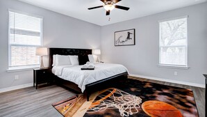 Ein Schlafzimmer mit Bett, Nachttischen, Deckenventilator und einem Teppich mit Basketballmotiv.