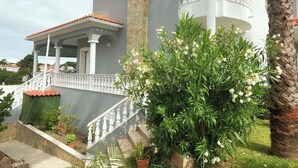 Une maison à deux étages dotée d’un balcon, d’un porche couvert et d’un mur en pierre.
