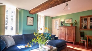 En hyggelig stue med en blå sofa, et træskab og en vase med blomster.