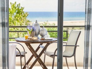 Un balcón con una mesa dispuesta para el desayuno, con vista a una playa.