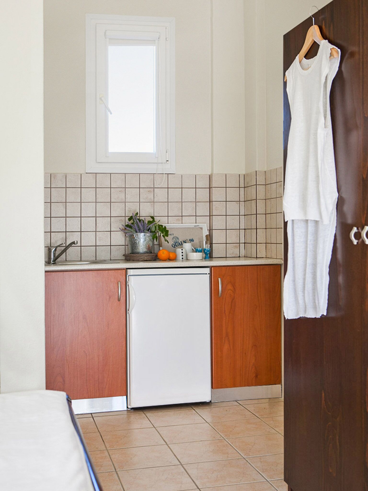 A compact kitchen with a refrigerator, a sink, and a window above the countertop.
