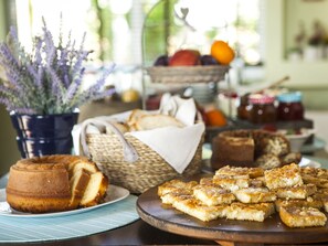 Una mesa con diferentes alimentos, como pan, bollería y una cesta de frutas.