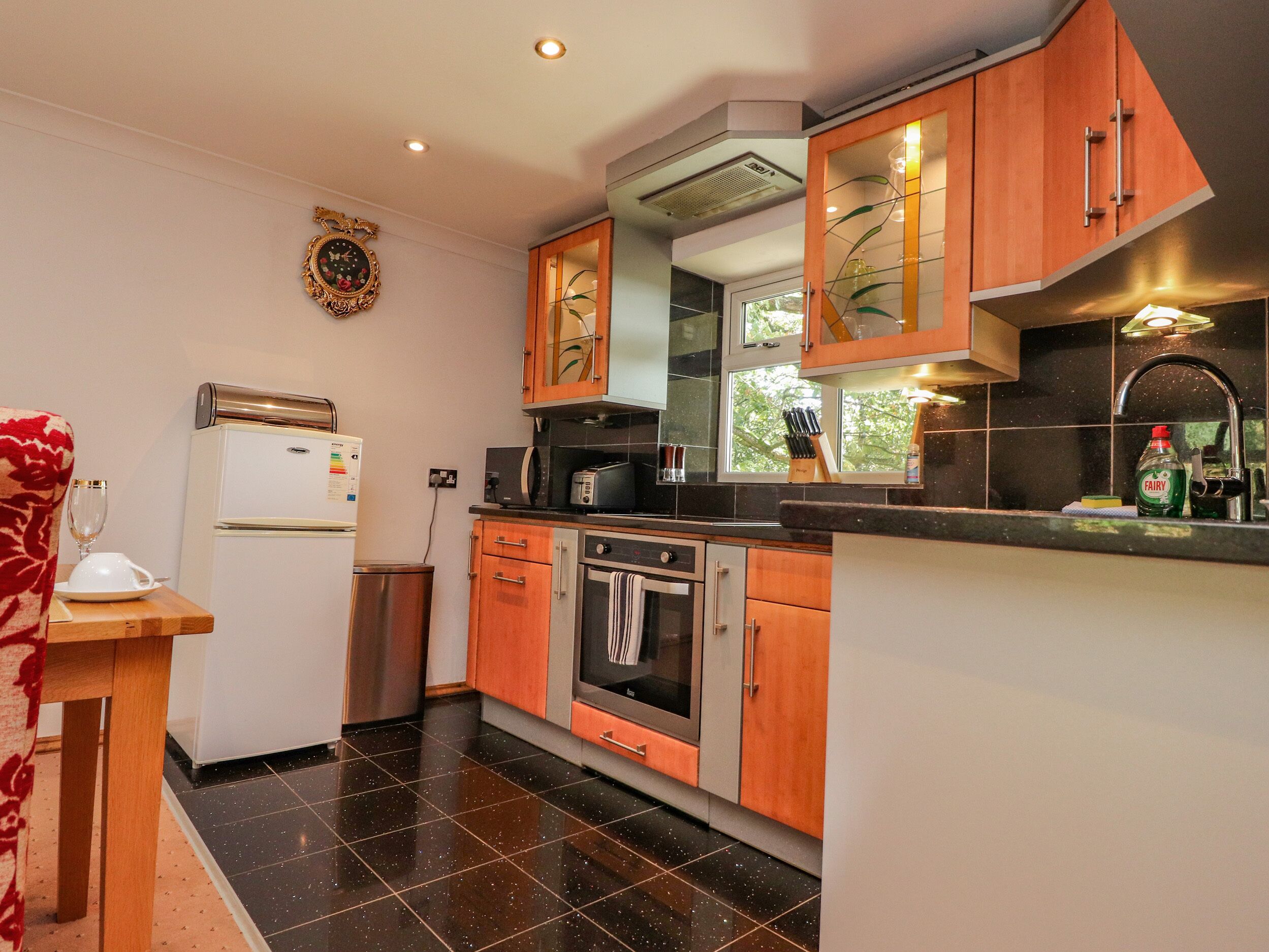 Een moderne keuken met een koelkast, oven, magnetron en een raam met uitzicht op groen.