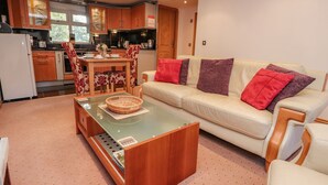 A compact living space with a dining area, a sofa, and a kitchen area. - Bronte Cottage (Keighley)