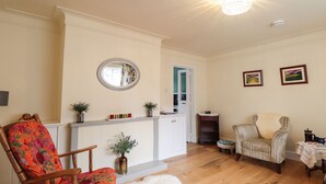 A living room with a wooden chair, a white fluffy rug, a wooden coffee table, and a small side table with a teapot.