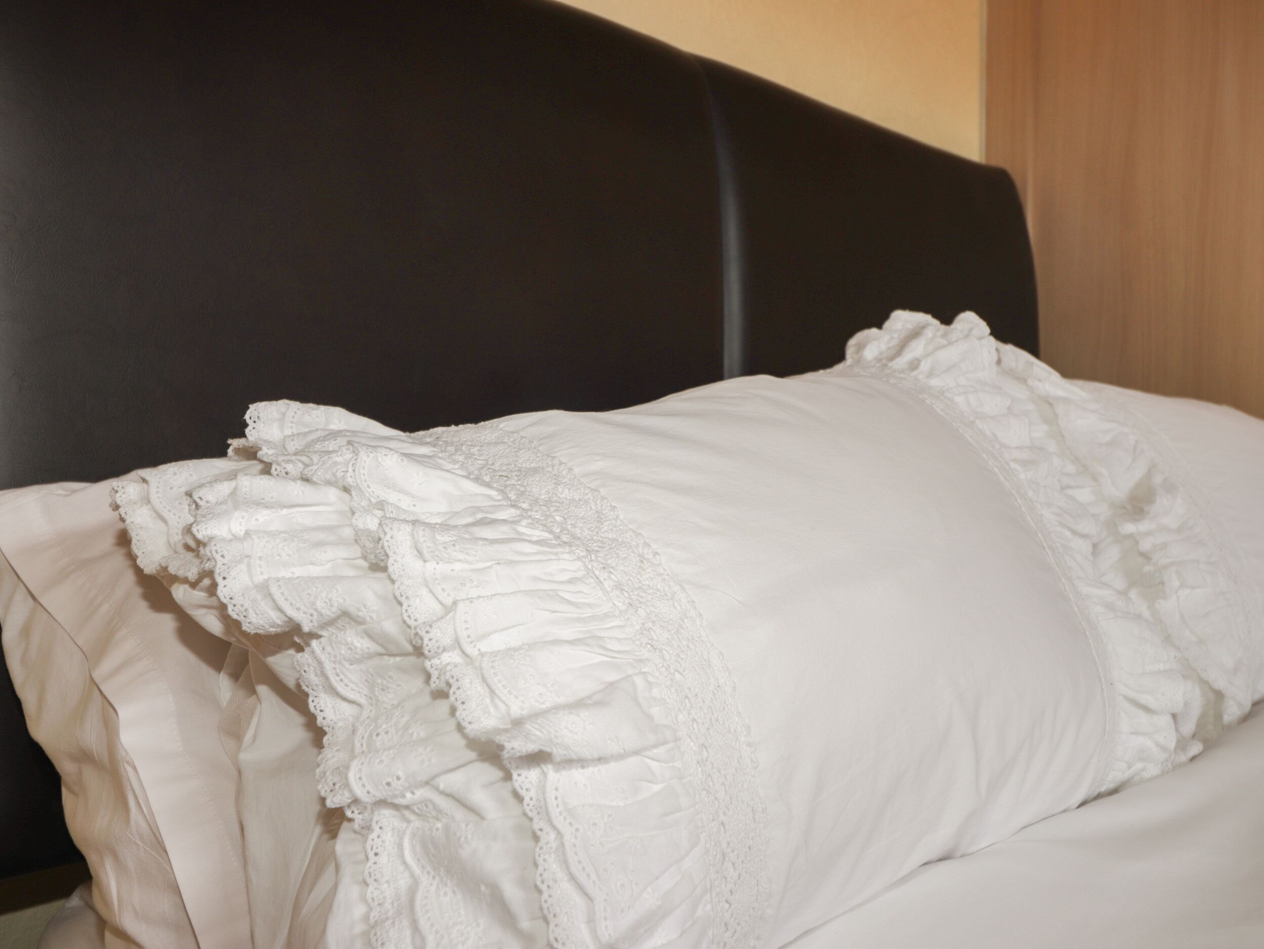 A bed with a white pillow and a black headboard.