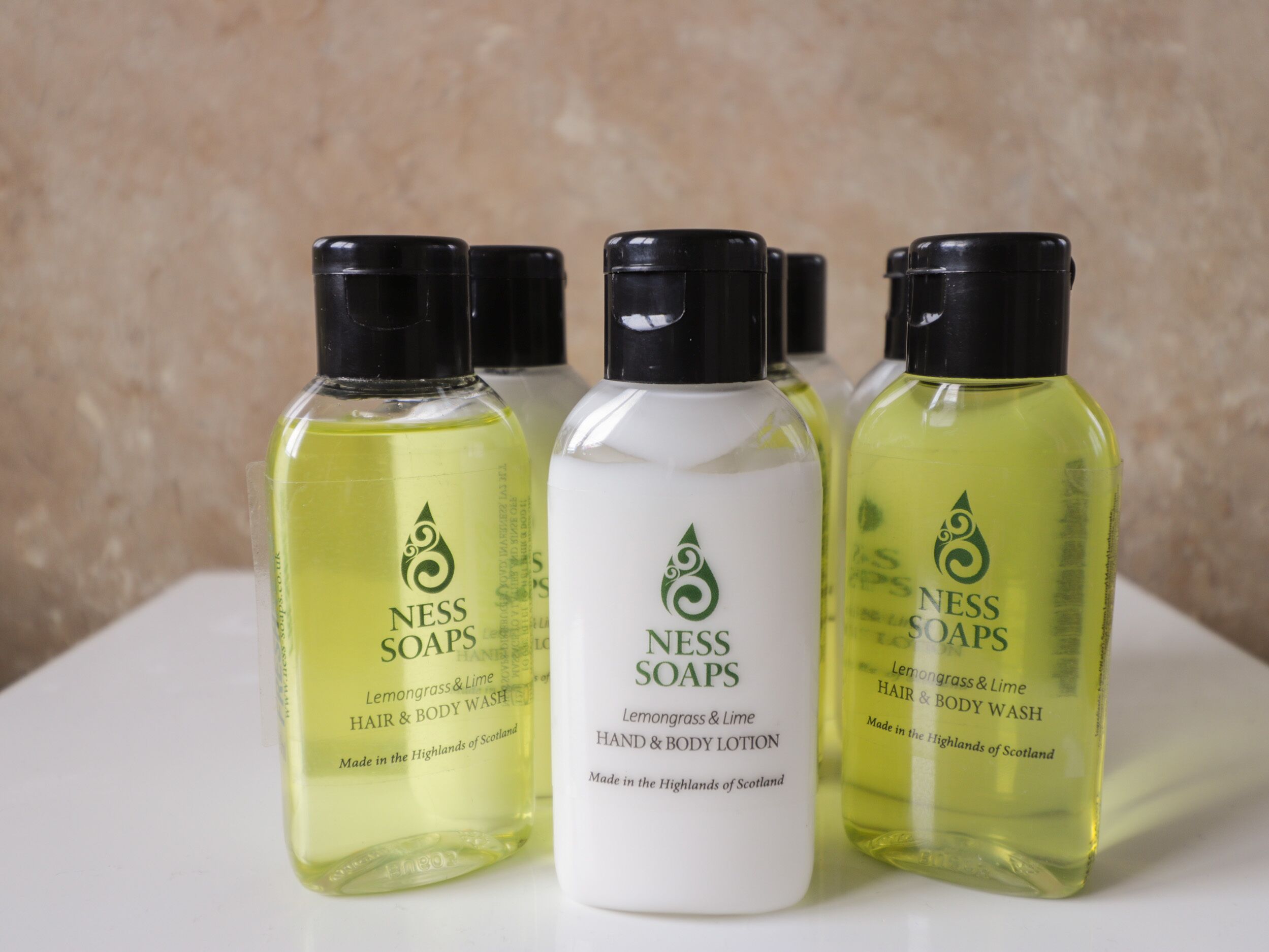 Four bottles of Ness Soaps, two in yellow and two in white, labeled as hair and body wash, made in the Highlands of Scotland.