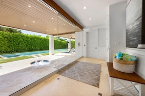 Un baño moderno con cabina de ducha de vidrio, techo de madera y vista a una piscina.