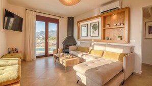 A modern living room with a sofa, a coffee table, and a fireplace. - Pool Villa close to Elafonisi (Kissamos)