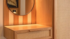A wooden vanity with a round mirror, a small stool, and a wall-mounted light fixture. - Pool Villa close to Elafonisi (Kissamos)
