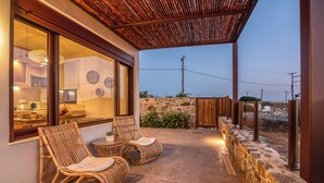A covered outdoor seating area with wicker chairs and a stone wall. - Pool Villa close to Elafonisi (Kissamos)